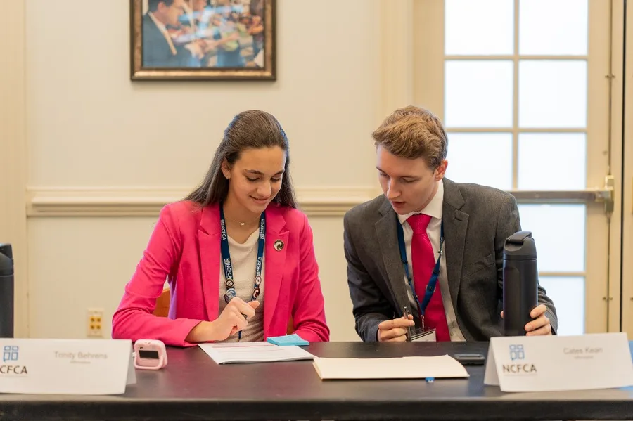 A Wavemakers Team Policy pair at the affirmative table during an NCFCA round